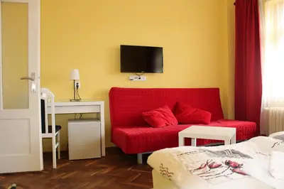 a living room with a red couch and a tv at Penzion Radost in Poděbrady