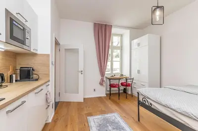 a bedroom with a bed and a kitchen with a table at Cozy quiet new apartment in Karlin square in Prague