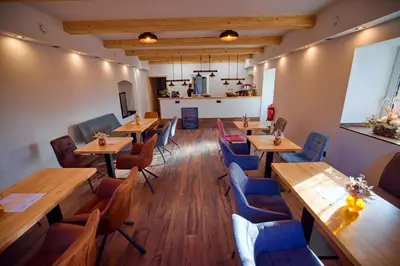 a restaurant with wooden tables and blue chairs at Penzion pod Hazmburkem in Klapý