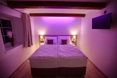 a bed in a room with a purple light at Penzion pod Hazmburkem in Klapý