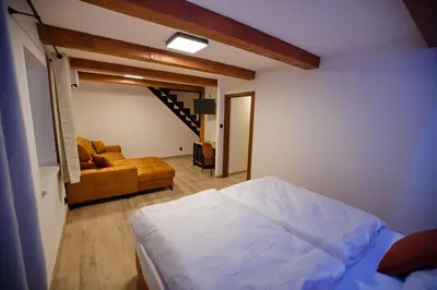 a bedroom with a bed and a living room with a couch at Penzion pod Hazmburkem in Klapý