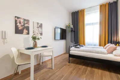 a bedroom with a bed and a table and a kitchen at Stay Inn Apartments U Stundanky in Prague