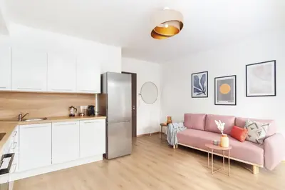 a living room with a pink couch and a kitchen at Prague Days - Studio with Balcony in quiet and trendy Holešovice in Prague