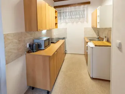 a kitchen with wooden cabinets and a microwave at Holiday Home Zimořský domek by Interhome in Dolní Zimoř