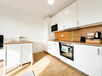 a kitchen with white cabinets and a wooden floor at Vila Vinice in Prague