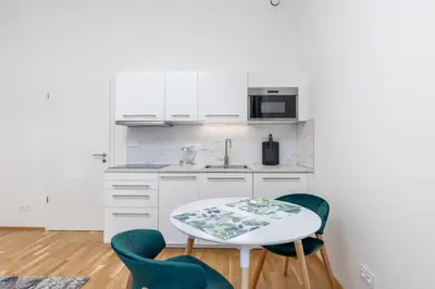 a kitchen with white cabinets and a table and chairs at Bright aparment close to Wenceslas square with parking in Prague