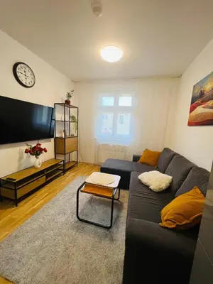a living room with a couch and a clock on the wall at Nika Apartments Prague 2 in Prague