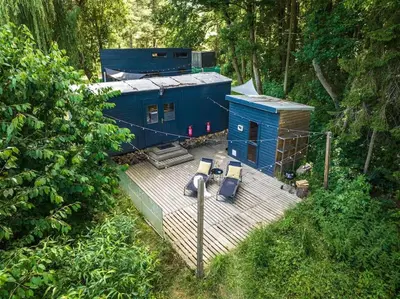 a blue building with two chairs on a deck at CozyTiny house at lake with sauna in Řehenice