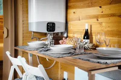 a dining room table with white dishes and wine glasses at CozyTiny house at lake with sauna in Řehenice