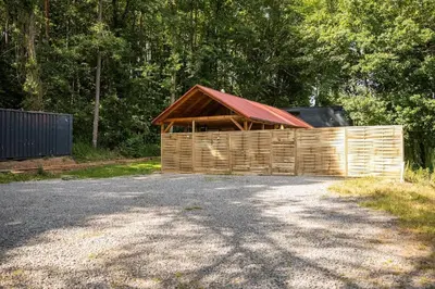 a wooden barn with a red roof on a road at CozyTiny house at lake with sauna in Řehenice