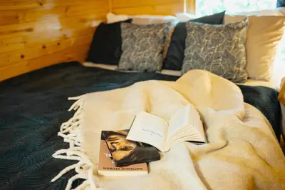 a book laying on top of a bed next to at CozyTiny house at lake with sauna in Řehenice