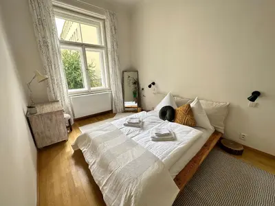 a bedroom with a large white bed with a window at 3BDR Bohemian style central flat with Balcony in Prague