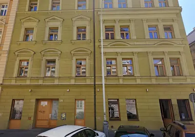 a yellow building with cars parked in front of it at Wooden Design 2BDR Apartment near Eden Garden in Prague