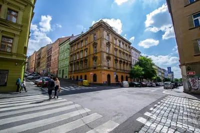 people crossing a street in a city with a building at Wooden Design 2BDR Apartment near Eden Garden in Prague