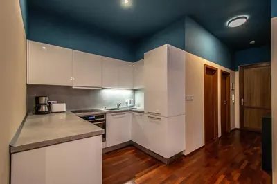 a kitchen with white cabinets and a blue wall at Wooden Design 2BDR Apartment near Eden Garden in Prague