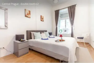 a white bedroom with a bed and a window at Kent Ridge Loft in Prague
