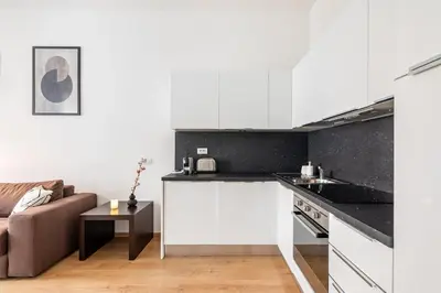 a kitchen with white cabinets and a couch at Place of Grace - 50 Meters from Dancing House in Prague