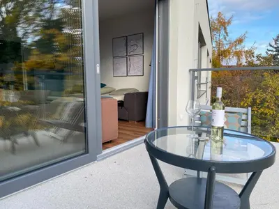 a glass table with a bottle of wine on a balcony at Klapka 08 in Prague