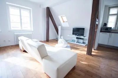 a living room with white furniture and a television at Apartments Old Town Square 27 in Prague