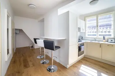 a kitchen with white cabinets and a bar stool at Apartments Old Town Square 27 in Prague