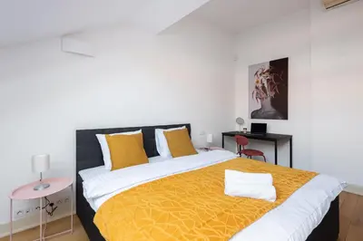 a bedroom with a bed and a desk and a window at Spacious apartments near the river Prague in Prague