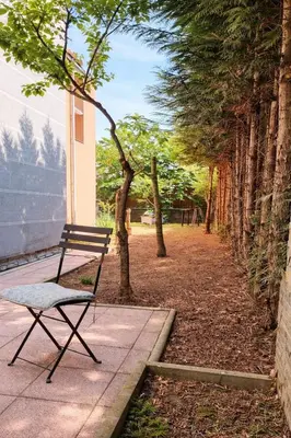 a bench sitting on a sidewalk next to trees at Garden Suite - KindStay Suites Prague Airport in Kněžívka