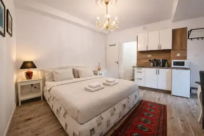 a bedroom with a large bed and a kitchen at Garden Suite - KindStay Suites Prague Airport in Kněžívka