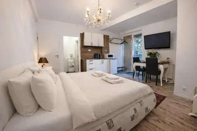 a bedroom with a white bed and a kitchen at Garden Suite - KindStay Suites Prague Airport in Kněžívka