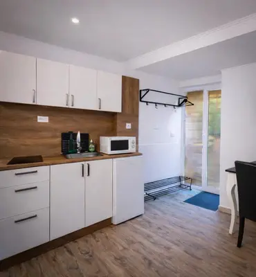 a kitchen with white cabinets and a microwave at Garden Suite - KindStay Suites Prague Airport in Kněžívka