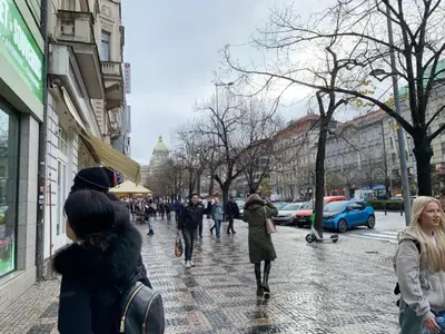 a group of people walking down a city street at TDC33-boo in Prague