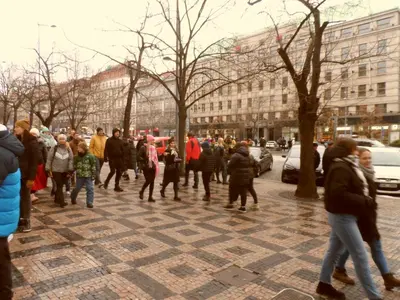 a group of people walking down a sidewalk at TDC33-boo in Prague