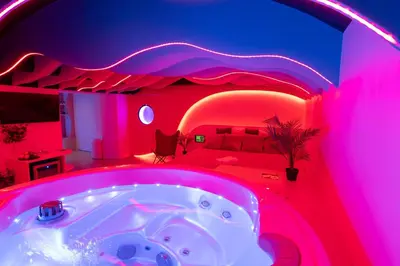 a bedroom with a bed and a tub in a room with pink lights at SPA SPA Legerova in Prague