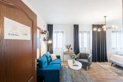 a living room with a blue couch and a bed at Penzion Dubina in Litoměřice