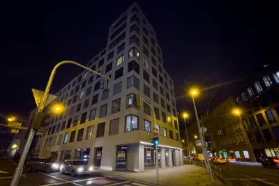 a tall white building on a city street at night at Residence My Mozart in Prague