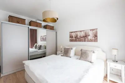 a white bedroom with a large white bed and a mirror at Jay Apartments in Prague