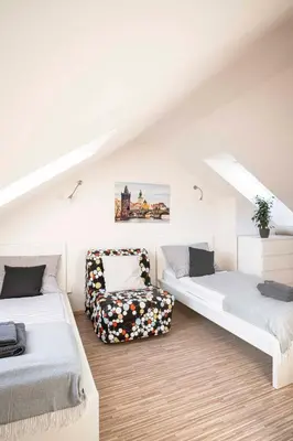 a attic room with two beds and a chair at 150m² 4BR Duplex Near Metro & Prague Center in Prague