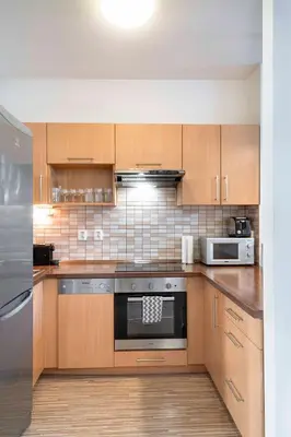 a kitchen with wooden cabinets and a stainless steel appliance at 150m² 4BR Duplex Near Metro & Prague Center in Prague