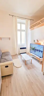 a living room with a large television and a bed at Cozy Karlín Loft City Center in Prague