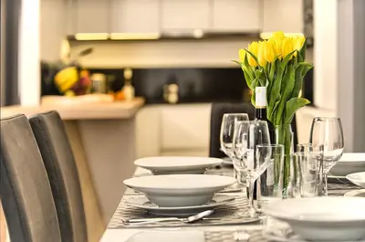 a table with glasses and a vase of yellow flowers at Exclusive 2 bedroom apartment Old Town - 2 baths, balcony and view - by Prague City Apartments in Prague