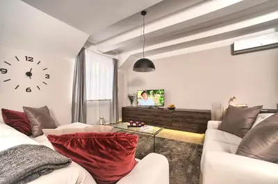 a living room with a couch and a clock on the wall at Exclusive 2 bedroom apartment Old Town - 2 baths, balcony and view - by Prague City Apartments in Prague