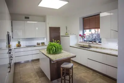 a kitchen with white cabinets and a counter with a stool at Luxury villa near Prague with pool and tennis court in Čestlice