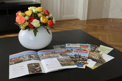 a book and a vase with flowers on a table at Royal Prague Apartment Celakovskeho Sady in Prague