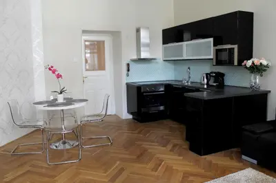 a kitchen with black cabinets and a table with chairs at Royal Prague Apartment Celakovskeho Sady in Prague