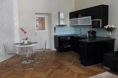 a kitchen with black cabinets and a table with chairs at Royal Prague Apartment Celakovskeho Sady in Prague