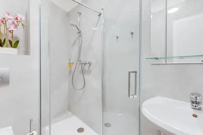 a white bathroom with a shower and a sink at Kafka Prague rooms in Prague