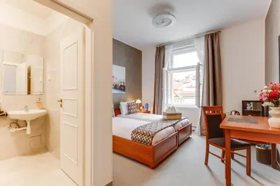 a bedroom with a bed and a sink and a desk at Kafka Prague rooms in Prague