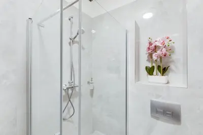 a shower with a glass door with flowers in it at Kafka Prague rooms in Prague