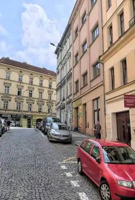 a red car parked on a cobblestone street next to buildings at Apartment Cimburkova in Prague