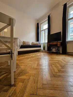 a living room with wooden floors and a bed and a television at Slezska Apartments in Prague