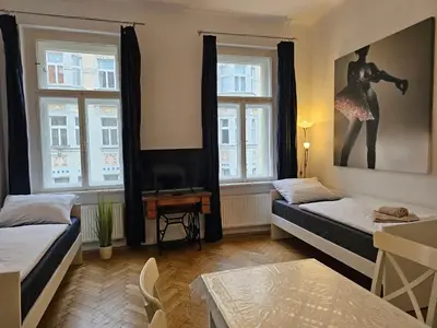 a room with two beds and a table and two windows at Slezska Apartments in Prague